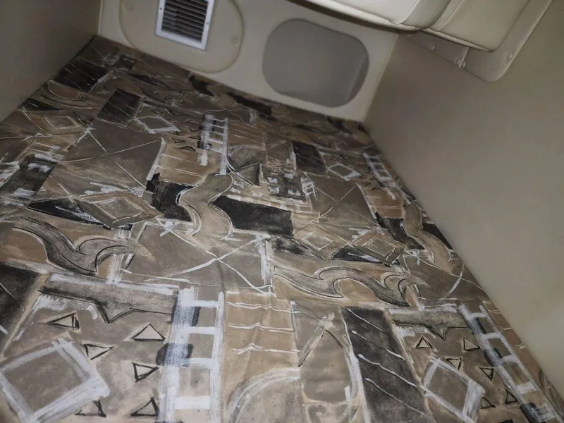 Slide: The Image of Interior cabin of 2000 Rinker 270 Express Cruiser with abstract patterned flooring. - 11