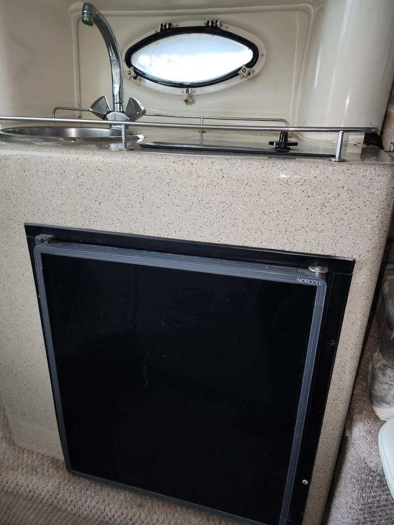 Slide: The Image of Compact kitchenette in 2000 Rinker 270 Express Cruiser with sink, faucet, and mini fridge. - 14