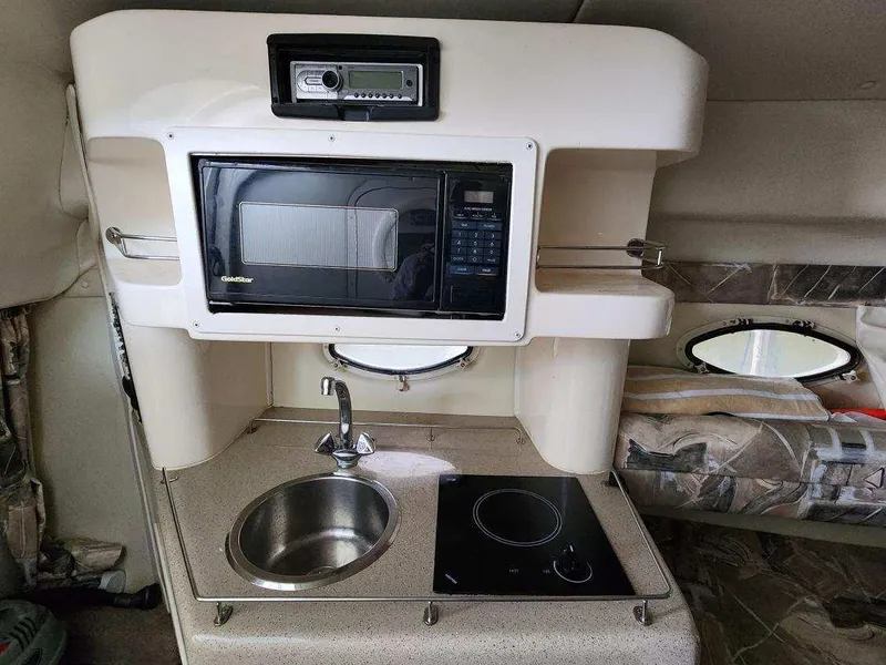 Slide: The Image of Compact kitchen area in a 2000 Rinker 270 Express Cruiser with microwave, sink, and stove. - 15
