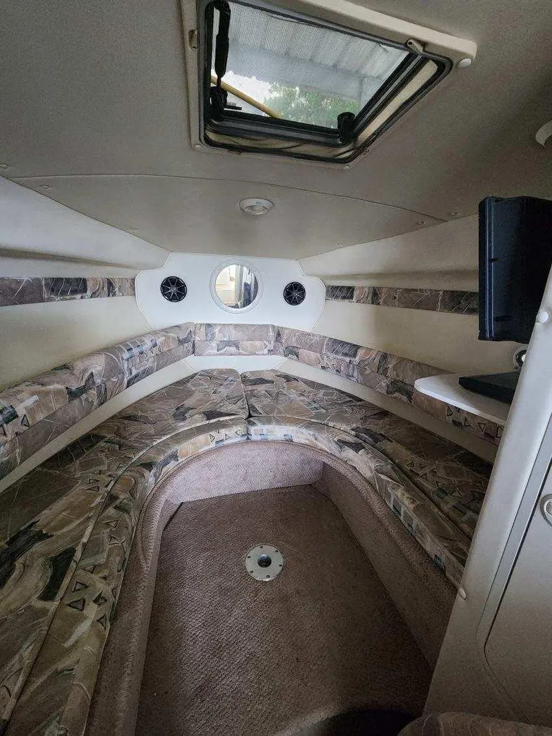Slide: The Image of Interior cabin of 2000 Rinker 270 Express Cruiser with patterned seating and porthole window. - 6