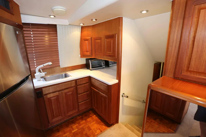 Slide: The Image of Compact kitchen in a 1991 Viking 50 Convertible yacht with wooden cabinets and stainless steel appliances. - 25