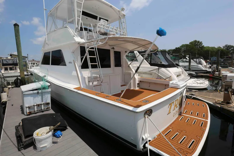 Slide: The Image of 1991 Viking 50 Convertible yacht docked at marina, featuring spacious deck and ladder. - 3