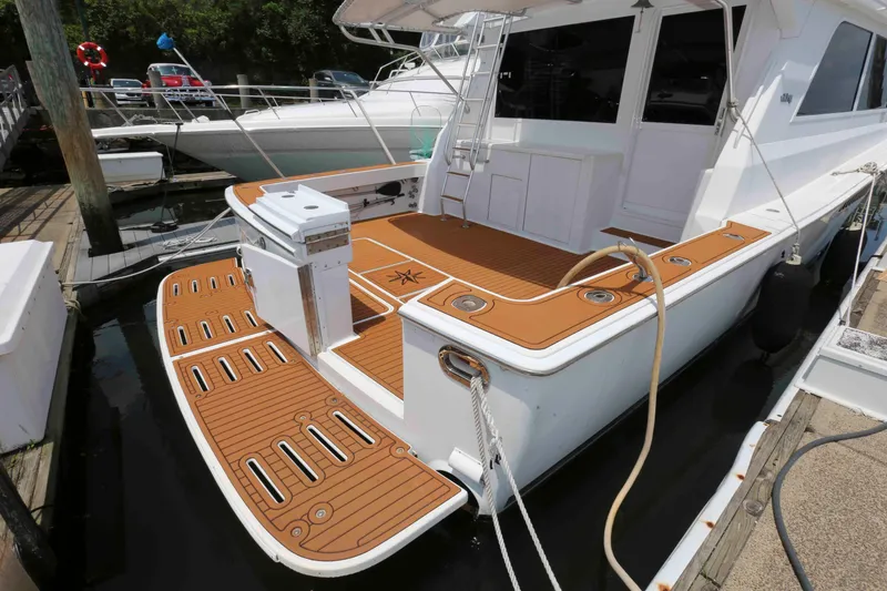 Slide: The Image of 1991 Viking 50 Convertible yacht docked, featuring a spacious teak deck and white exterior. - 5