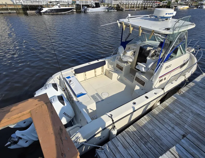 Slide: The Image of 1996 Stratos 2500 Walkaround boat docked, featuring spacious deck and dual Honda outboard engines. - 4