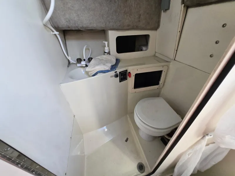 Slide: The Image of 1996 Stratos 2500 Walkaround boat bathroom with sink, toilet, and storage compartments. - 9