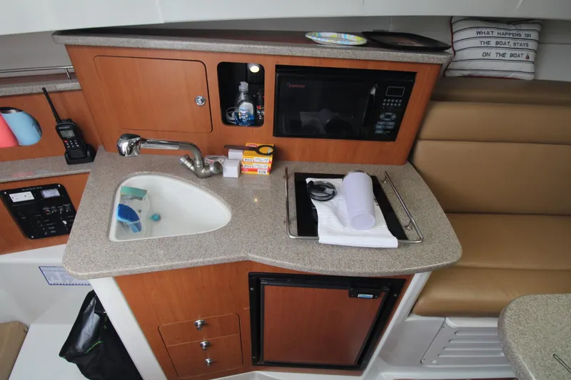 Slide: The Image of Compact kitchen area in a 2007 Sailfish 3006 WALKAROUND boat with sink, microwave, and storage. - 20