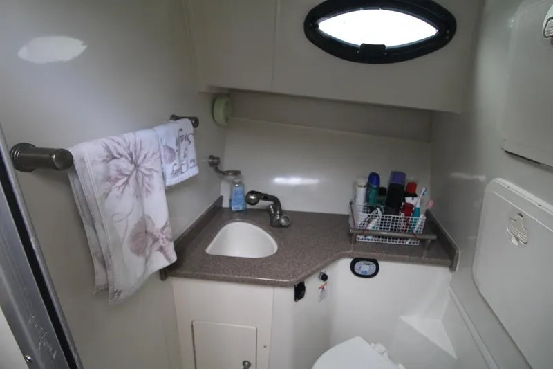 Slide: The Image of Compact bathroom in 2007 Sailfish 3006 WALKAROUND boat with sink, toiletries, and towel rack. - 26