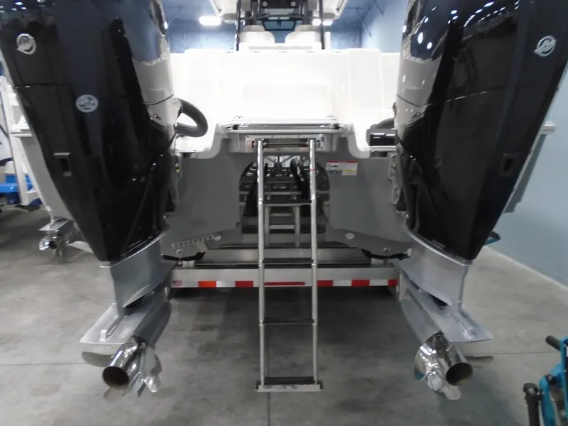 Slide: The Image of 2026 Caymas 34 CT boat with dual outboard motors and rear ladder in a showroom. - 9