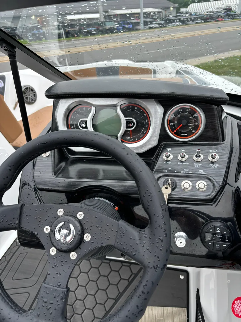 Slide: The Image of 2024 Scarab 215 H.O. Platinum dashboard with steering wheel and controls, wet from rain. - 7