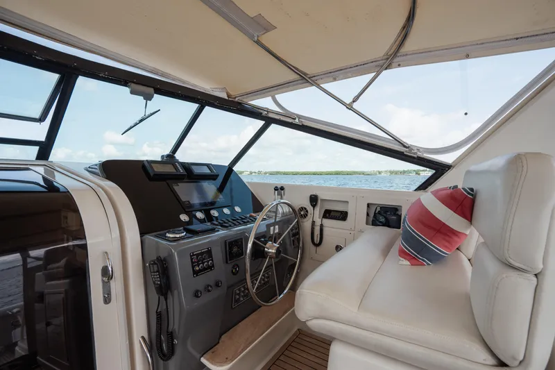 Slide: The Image of 1998 Tiara Yachts 4300 Open helm with steering wheel, controls, and striped cushion. - 31