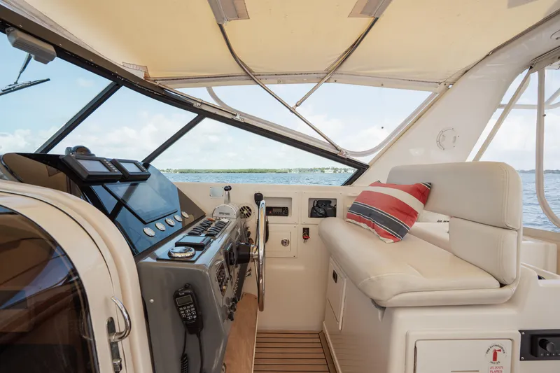 Slide: The Image of 1998 Tiara Yachts 4300 Open helm with modern controls and striped cushion. - 34