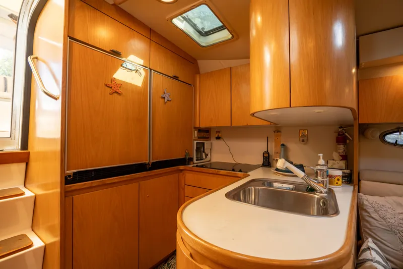 Slide: The Image of 1998 Tiara Yachts 4300 Open kitchen with wooden cabinets and stainless steel sink. - 49