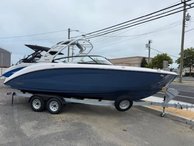 The Image of 2025 Yamaha Boats 252S on trailer, blue hull, parked outdoors. - 0