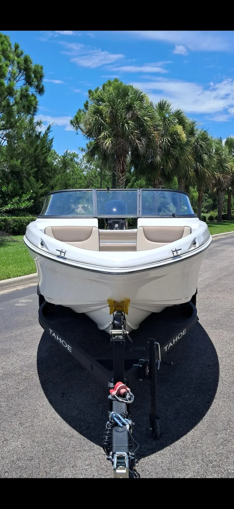 Slide: The Image of 2025 Tahoe 200 S boat on trailer, parked on a sunny road with lush greenery. - 2