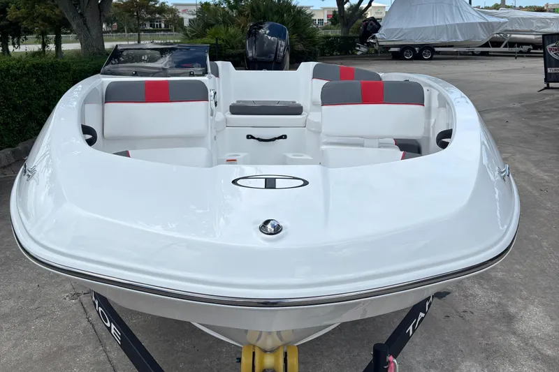 Slide: The Image of 2025 Tahoe T16 boat with white and red seating, parked on a trailer. - 2