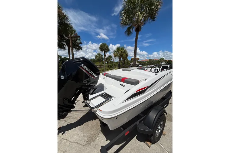 Slide: The Image of 2025 Tahoe T16 boat with Mercury engine, parked under palm trees on a sunny day. - 5