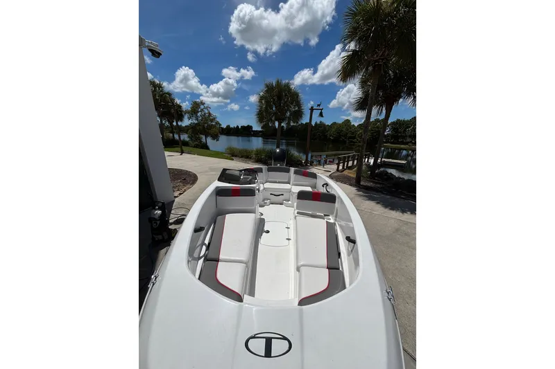 Slide: The Image of 2025 Tahoe T16 boat docked by a scenic lake under a clear blue sky. - 1