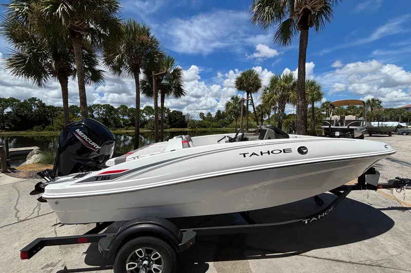 The Image of 2025 Tahoe T16 boat on trailer, parked near palm trees under a clear blue sky. - 0