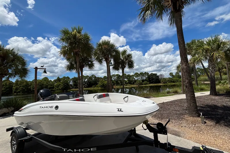 Slide: The Image of 2025 Tahoe T16 boat on trailer by palm trees and lake under blue sky. - 10