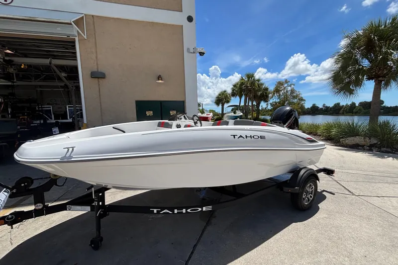 Slide: The Image of 2025 Tahoe T16 boat on trailer, parked near a lake with palm trees. - 2