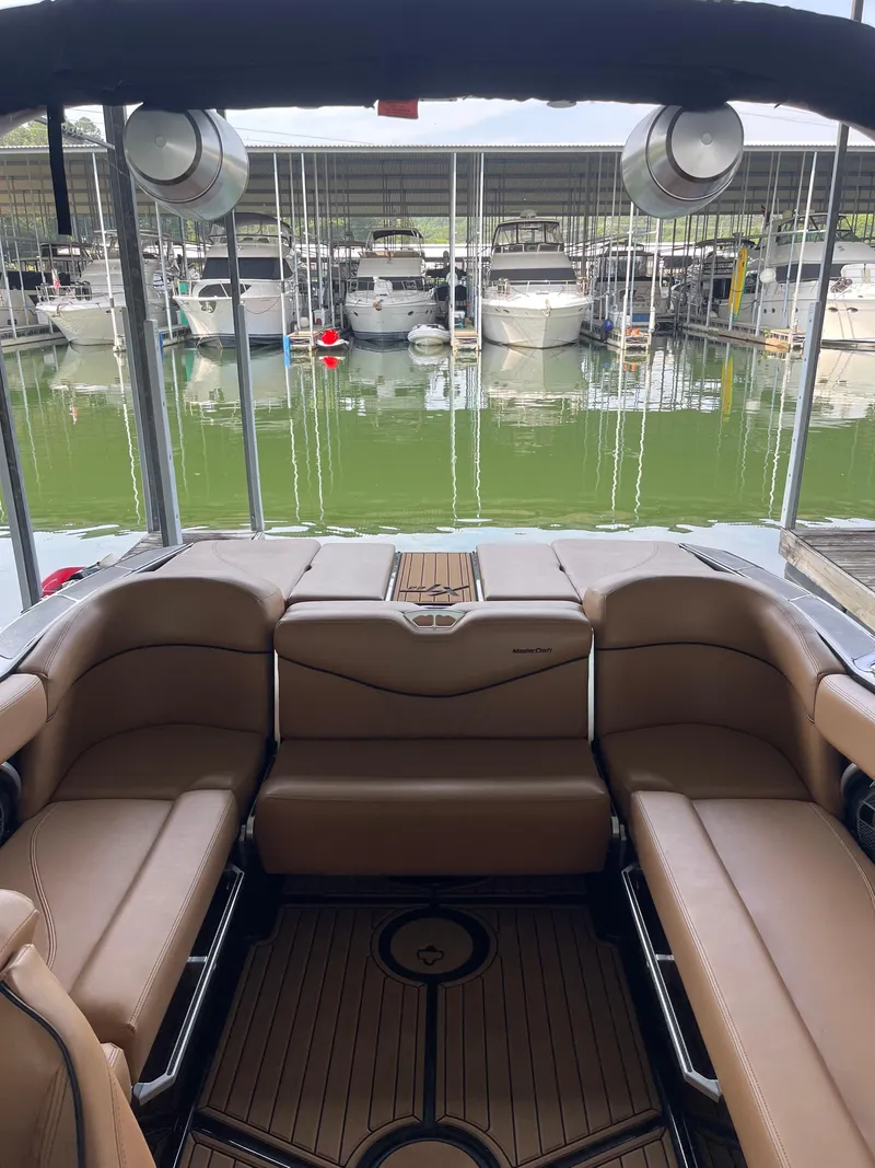 Slide: The Image of 2020 MasterCraft XT23 boat interior with tan seating, docked at marina. - 3