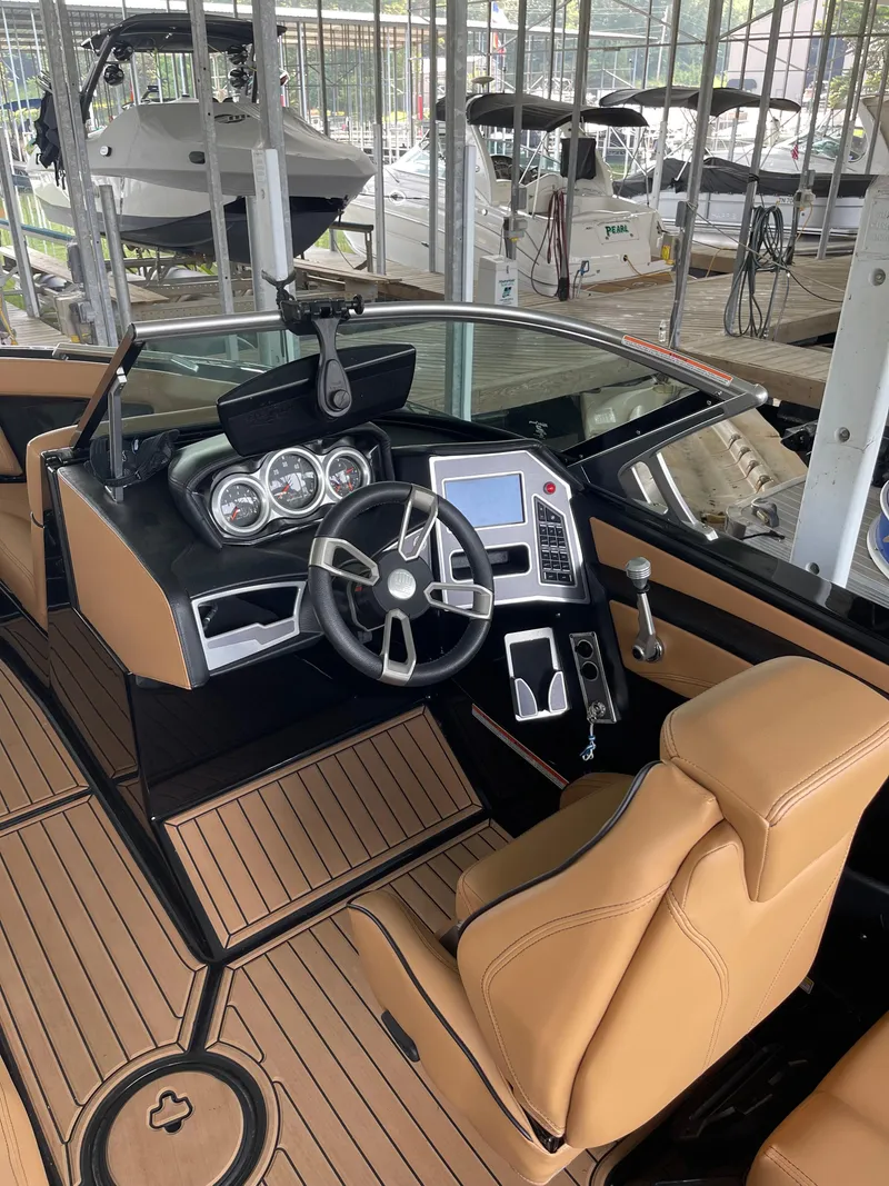 Slide: The Image of 2020 MasterCraft XT23 boat interior with tan seats and modern dashboard in a marina. - 4