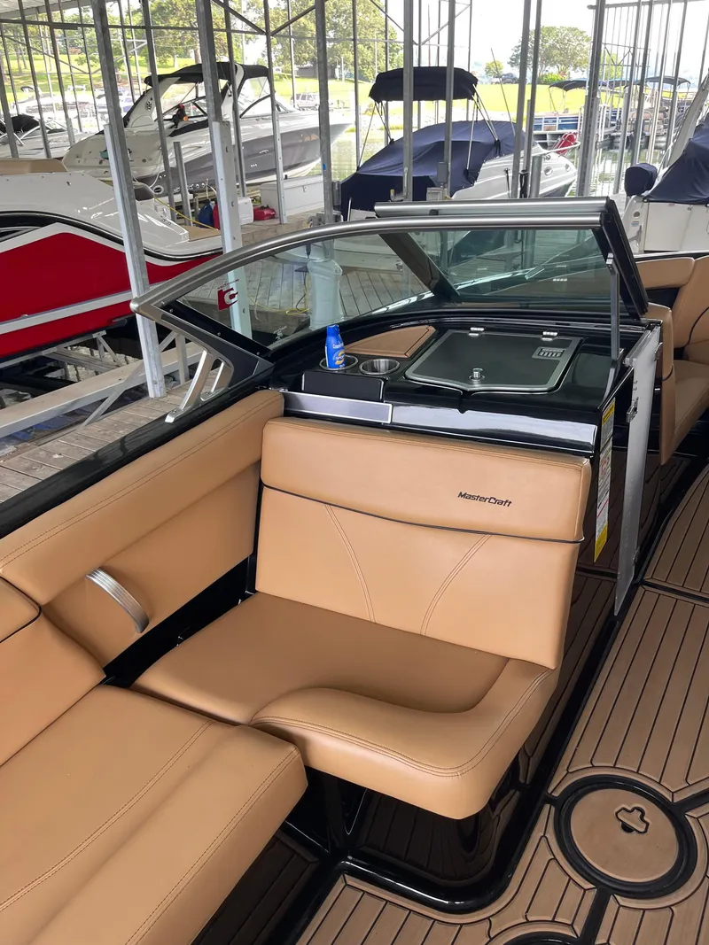 Slide: The Image of 2020 MasterCraft XT23 boat interior with tan seating and sleek design in a marina. - 5