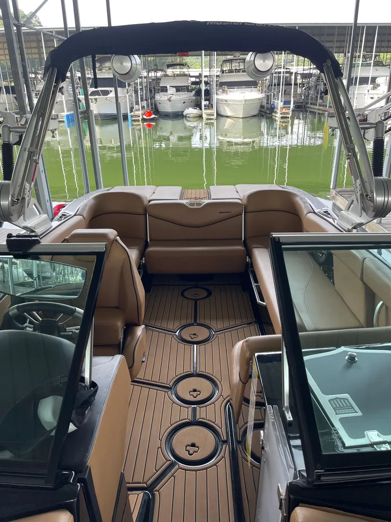 Slide: The Image of 2020 MasterCraft XT23 boat interior with tan seating and wood-style flooring, docked at marina. - 7