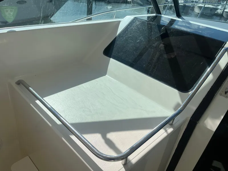 Slide: The Image of 1989 Tiara Yachts 33OPEN cockpit area with railing and window, docked at marina. - 10