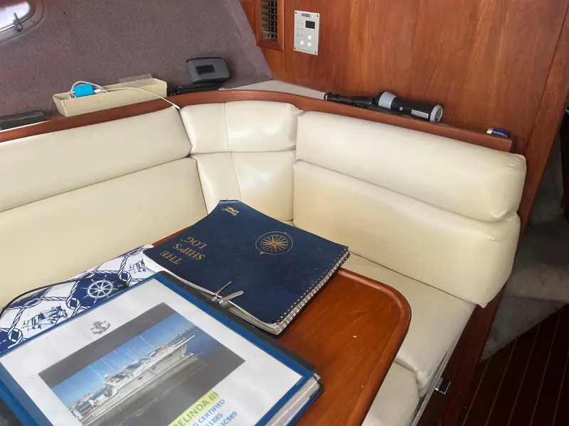 Slide: The Image of 1989 Tiara Yachts 33OPEN interior with beige seating and ship logs on table. - 18
