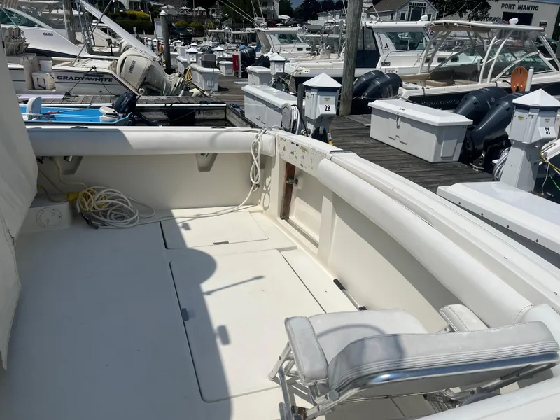 Slide: The Image of 1989 Tiara Yachts 33OPEN boat interior at marina, featuring white seating and docked vessels. - 2