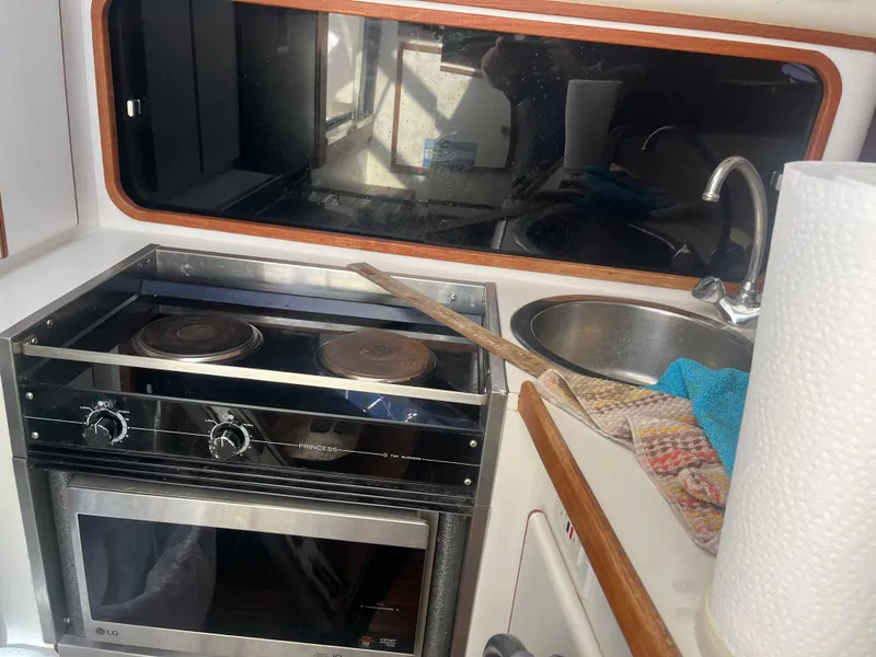 Slide: The Image of Compact kitchen area in a 1989 Tiara Yachts 33OPEN, featuring stove, sink, and window. - 21