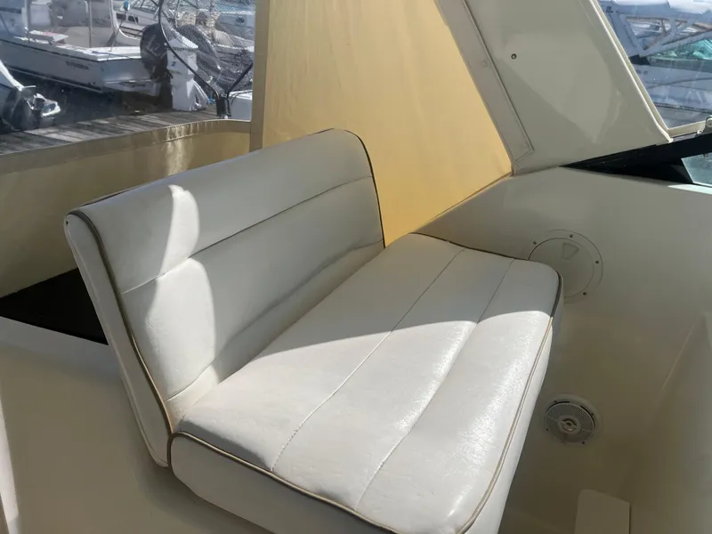 Slide: The Image of White leather seating on 1989 Tiara Yachts 33OPEN, with marina view in background. - 7
