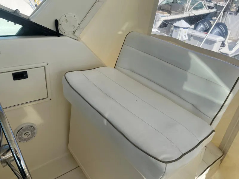 Slide: The Image of 1989 Tiara Yachts 33OPEN interior with white cushioned seating and window view. - 8