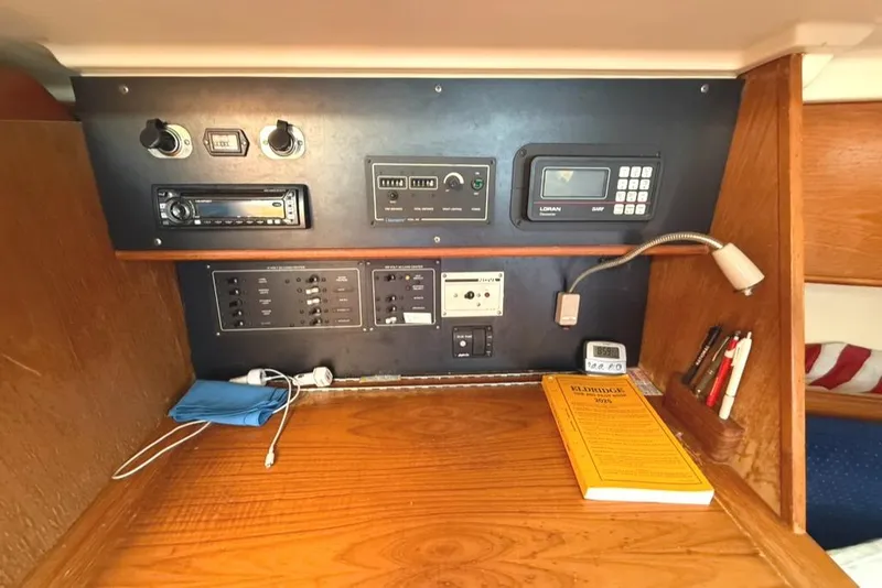 Slide: The Image of Navigation station inside a 1986 Pearson 33-2 sailboat with control panels and equipment. - 24