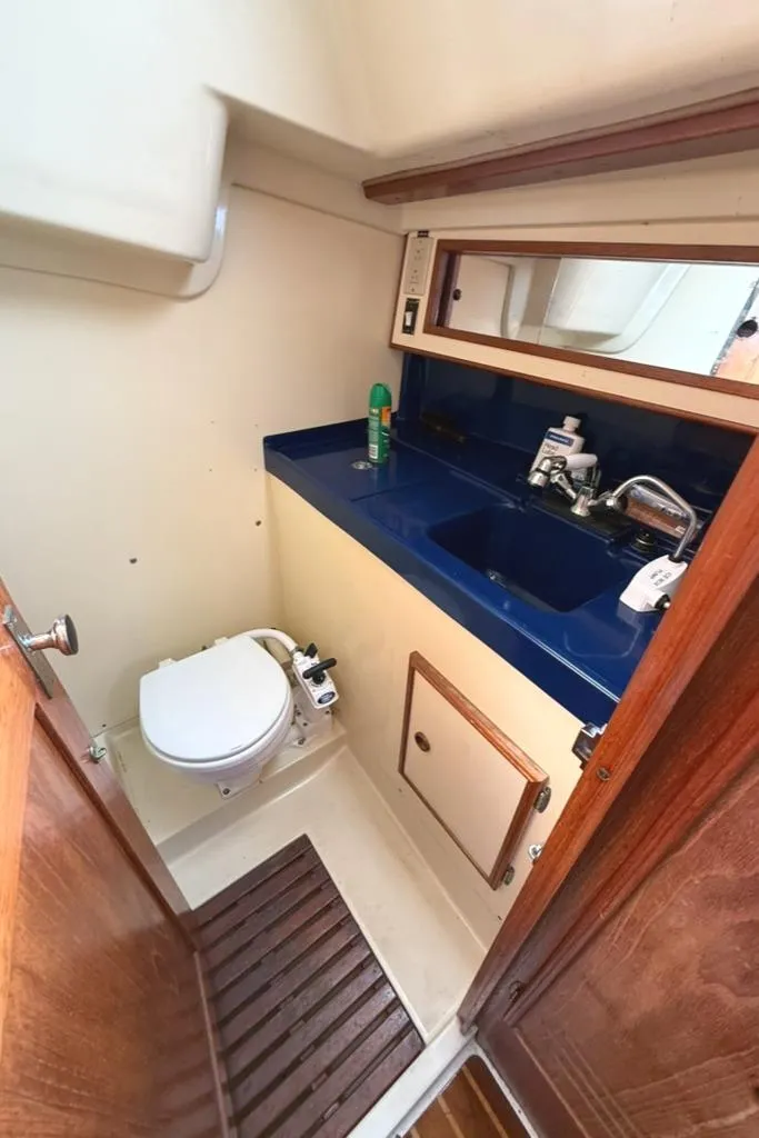 Slide: The Image of 1986 Pearson 33-2 yacht bathroom with blue sink, toilet, and wooden accents. - 26