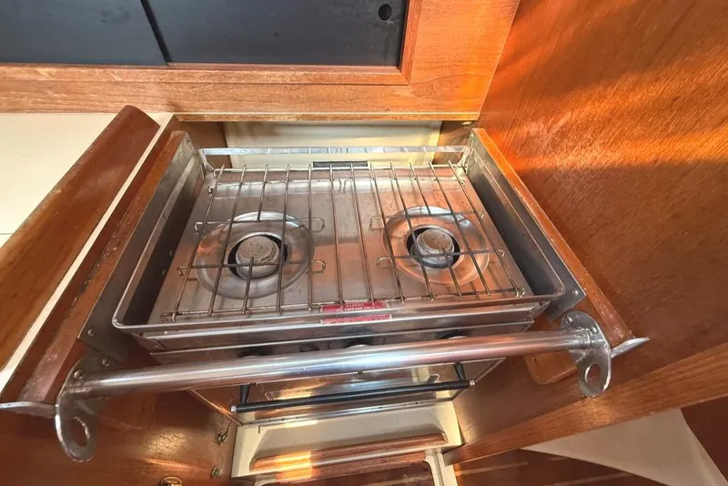 Slide: The Image of Two-burner stove in a 1986 Pearson 33-2 sailboat galley, surrounded by wooden cabinetry. - 33