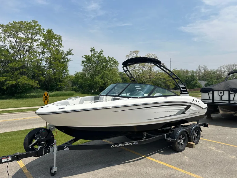 Slide: The Image of 2025 Chaparral 21 SSi boat on trailer, parked outdoors under a clear sky. - 3