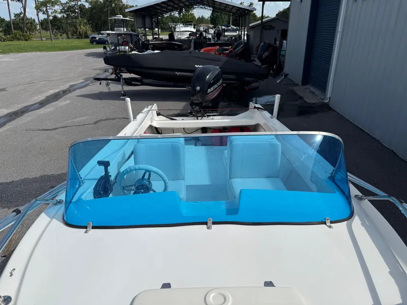 Slide: The Image of 1963 T Craft VHULL boat with blue windshield and white interior, parked near other boats. - 4