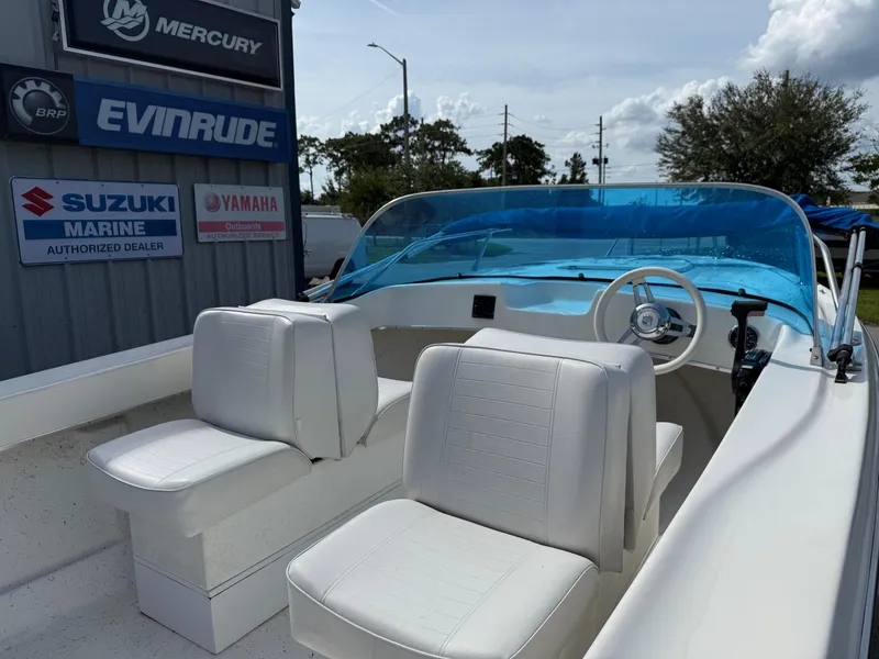 Slide: The Image of 1963 T Craft VHULL boat with white seats and blue windshield, near marine dealer signs. - 7