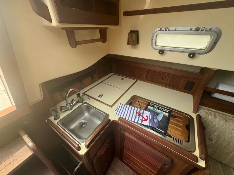 Slide: The Image of 1986 Island Packet IP27 Cutter galley with sink, stove, and wooden cabinetry. - 21