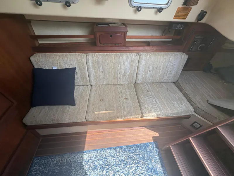 Slide: The Image of Interior of 1986 Island Packet IP27 Cutter with beige cushions and a navy pillow. - 24