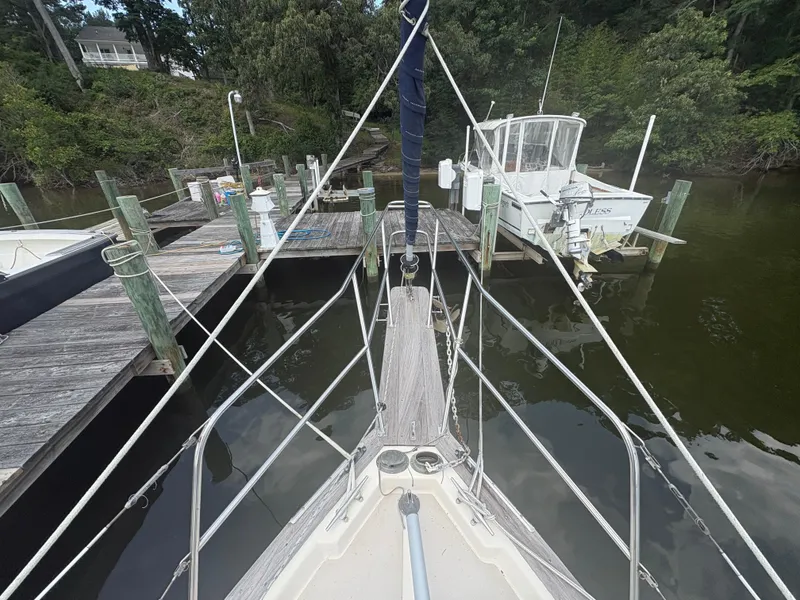 Slide: The Image of 1986 Island Packet IP27 Cutter docked at a wooden pier, surrounded by lush greenery. - 3