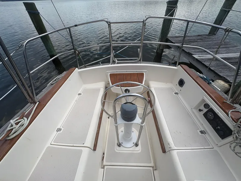 Slide: The Image of 1986 Island Packet IP27 Cutter cockpit with steering wheel, docked by calm water. - 32
