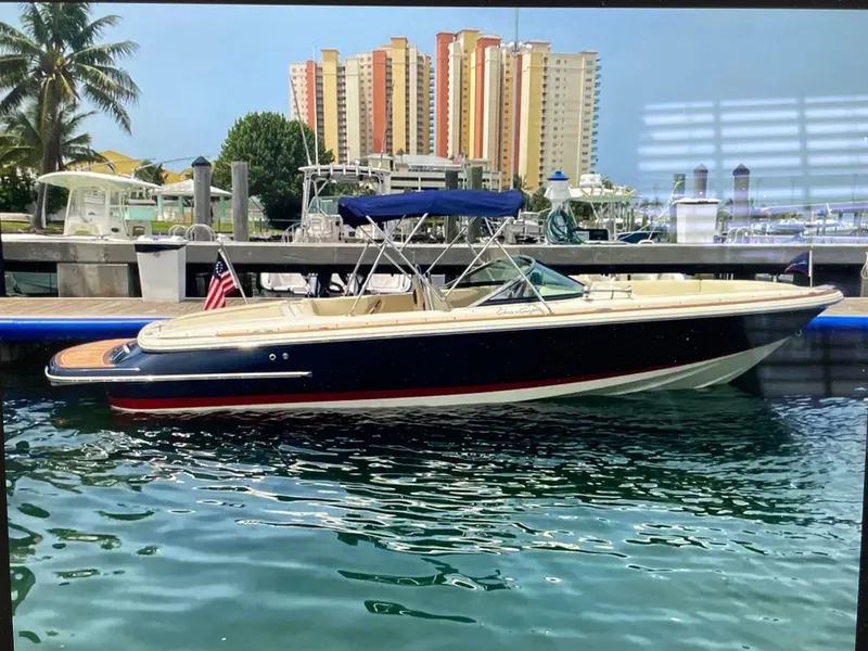 The Image of 2020 Chris-Craft Launch 23 boat docked in marina, with cityscape and palm trees in background. - 0