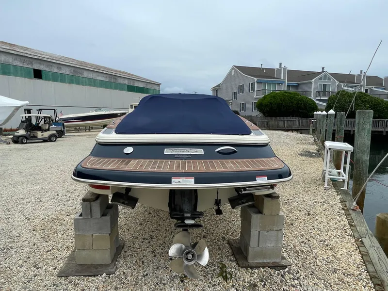 Slide: The Image of 2020 Chris-Craft Launch 23 boat on blocks, covered, near waterfront homes. - 5