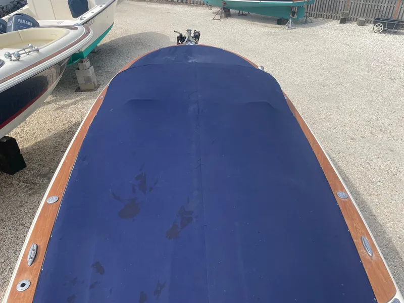 Slide: The Image of 2020 Chris-Craft Launch 23 boat with blue cover, parked on gravel. - 7