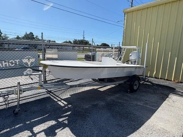 Slide: The Image of 2025 Mitzi Skiff 15 boat on trailer, parked outdoors near a yellow building. - 2