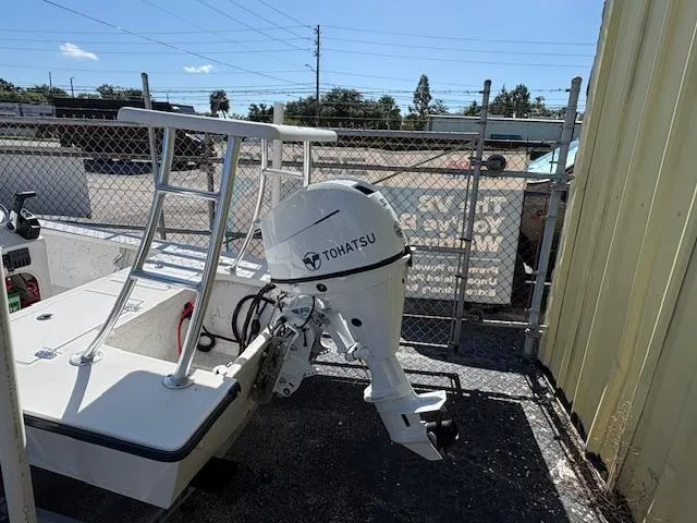 Slide: The Image of 2025 Mitzi Skiff 15 with Tohatsu outboard motor, parked near a chain-link fence. - 5