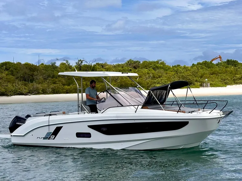 Slide: The Image of 2023 Beneteau Flyer 9 SUNdeck boat cruising near a sandy beach and lush greenery. - 4